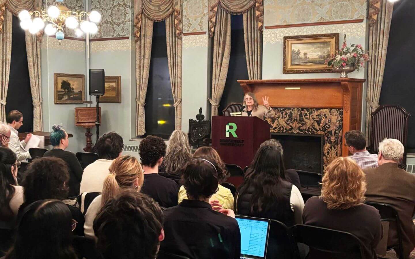 Dr. Sullivan standing in front of podium, delivering a lecture to an audience of Roosevelt students, faculty and local community members.