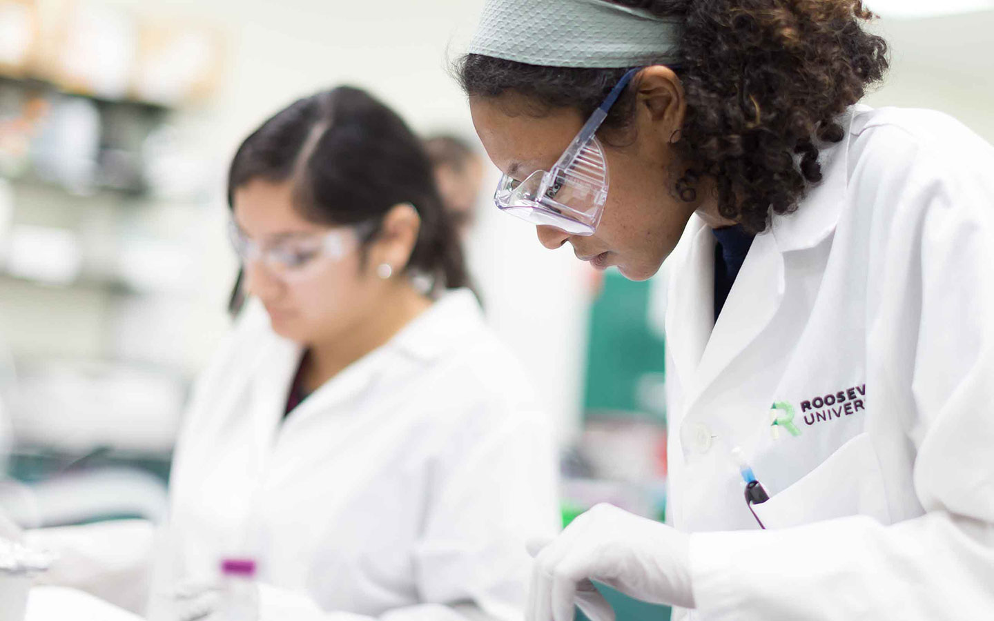 Two students wearing Roosevelt labcoats working in a classroom lab