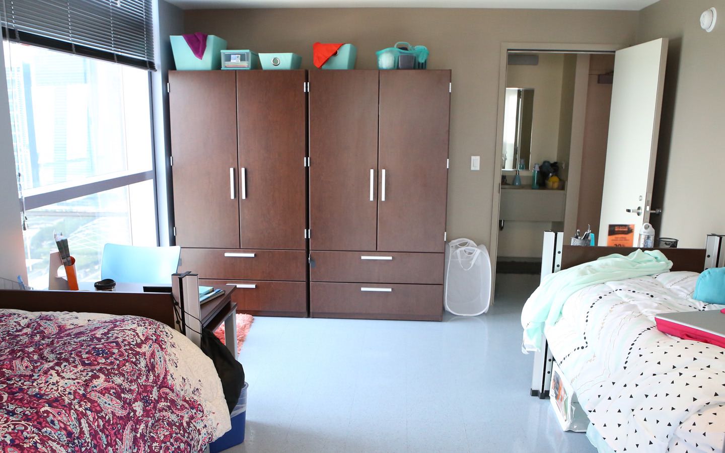 View of a double-occupancy dorm room featuring wardrobes and door to private restroom..