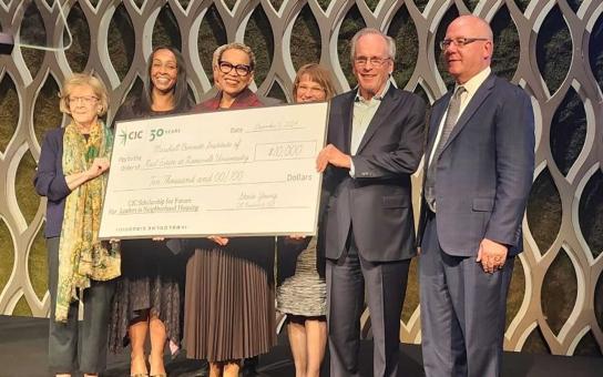 Executive Director of the Marshall Bennett Institute of Real Estate Collete English-Dixon holds up a donation check for the CIC Scholarship for Future Leaders in Neighborhood Housing 