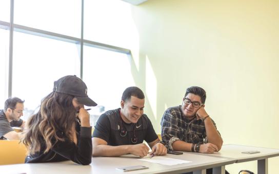 Three students sitting together at a classroom table